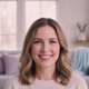 Smiling woman in her late 30s, natural makeup, genuine expression, blurred modern living space background with soft lilac and